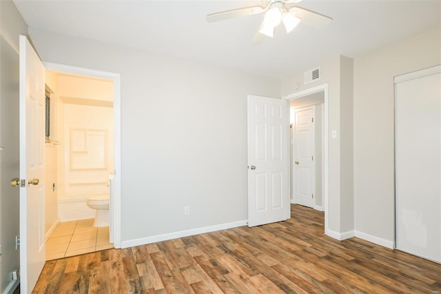 unfurnished bedroom featuring wood-type flooring, connected bathroom, a closet, and ceiling fan