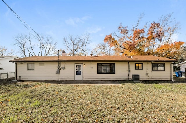 rear view of property featuring central AC and a lawn