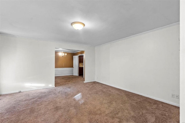 carpeted empty room featuring a chandelier and ornamental molding