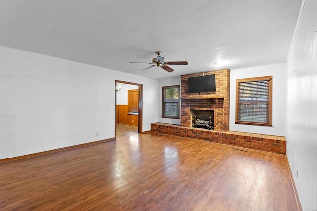 unfurnished living room with ceiling fan, wood-type flooring, and a brick fireplace