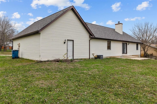 rear view of property with central AC and a yard