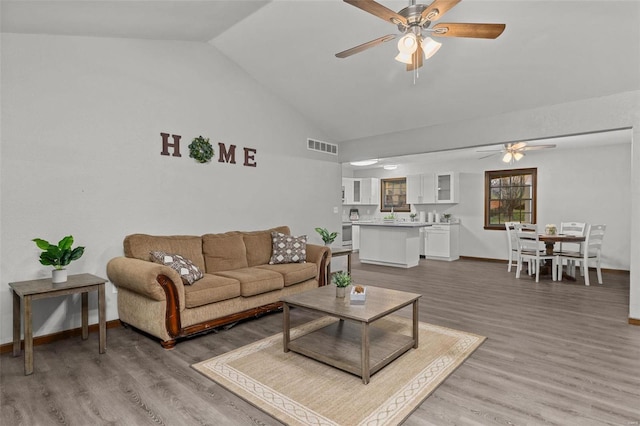 living room with hardwood / wood-style floors, vaulted ceiling, and ceiling fan