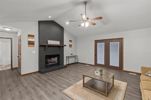 living room with a fireplace, hardwood / wood-style flooring, vaulted ceiling, and ceiling fan