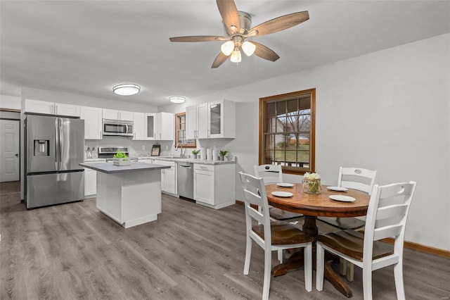 kitchen featuring stainless steel appliances, ceiling fan, light hardwood / wood-style flooring, white cabinets, and a kitchen island