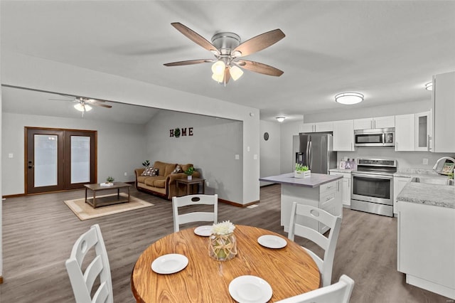 dining room with wood-type flooring, ceiling fan, lofted ceiling, and sink