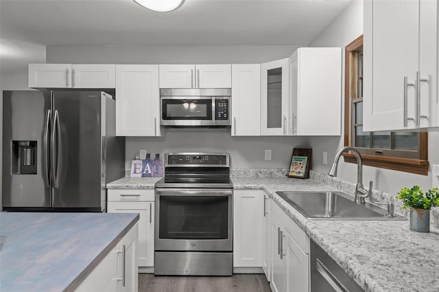 kitchen featuring light stone countertops, sink, dark wood-type flooring, stainless steel appliances, and white cabinets