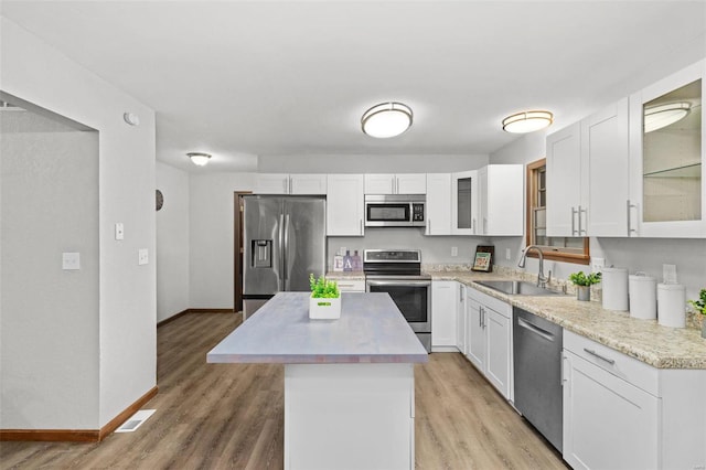 kitchen featuring white cabinetry, a center island, stainless steel appliances, and light wood-type flooring