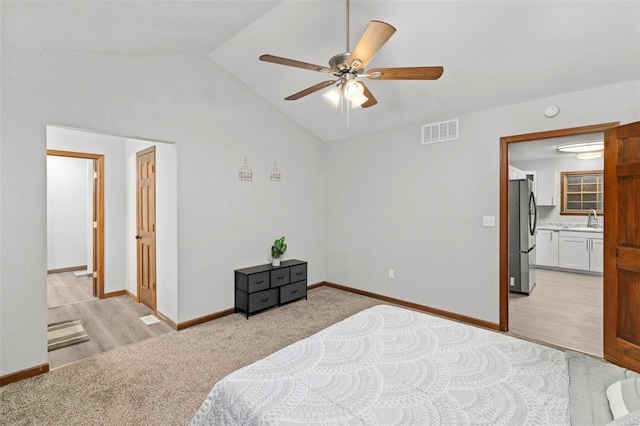 bedroom with ensuite bath, vaulted ceiling, ceiling fan, sink, and stainless steel refrigerator