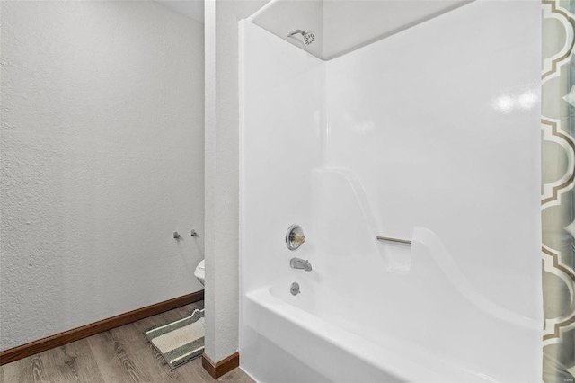 bathroom featuring bathing tub / shower combination, toilet, and hardwood / wood-style flooring