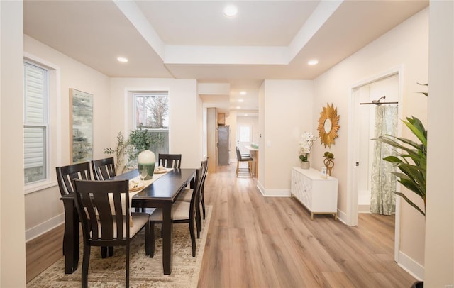 dining room featuring a raised ceiling and light hardwood / wood-style flooring