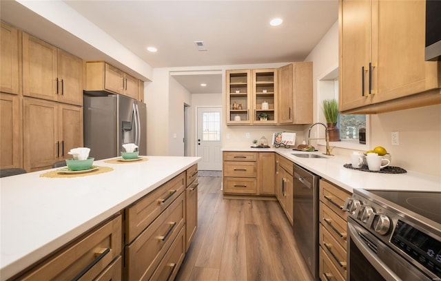 kitchen featuring stainless steel appliances, sink, light brown cabinetry, and light wood-type flooring