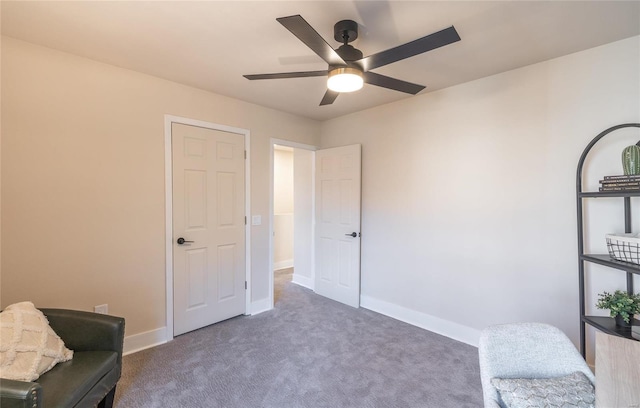 sitting room with ceiling fan and dark colored carpet