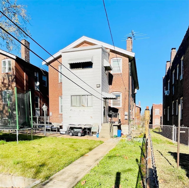 back of property featuring a trampoline and a yard