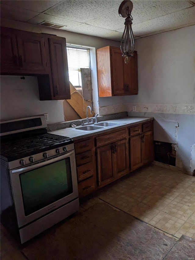 kitchen featuring stainless steel range with gas cooktop, sink, and decorative light fixtures