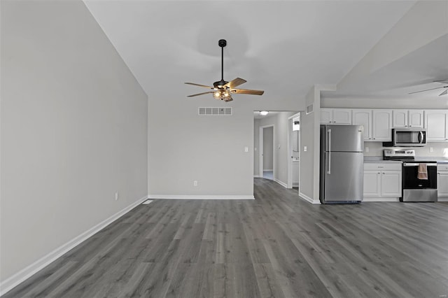 kitchen with lofted ceiling, white cabinets, hardwood / wood-style flooring, ceiling fan, and stainless steel appliances