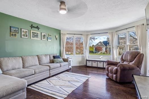 living room featuring a textured ceiling, ceiling fan, and dark wood-type flooring