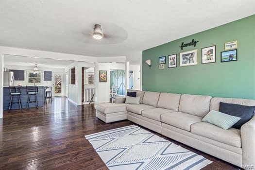 living room featuring ceiling fan and dark hardwood / wood-style floors