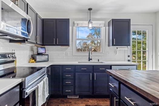 kitchen featuring sink, tasteful backsplash, butcher block countertops, pendant lighting, and appliances with stainless steel finishes