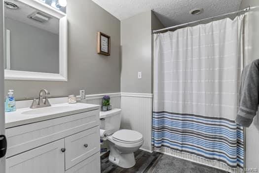 bathroom featuring wood-type flooring, a textured ceiling, toilet, vanity, and a shower with shower curtain