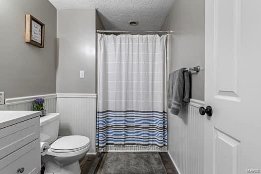 bathroom with a shower with shower curtain, vanity, toilet, and a textured ceiling