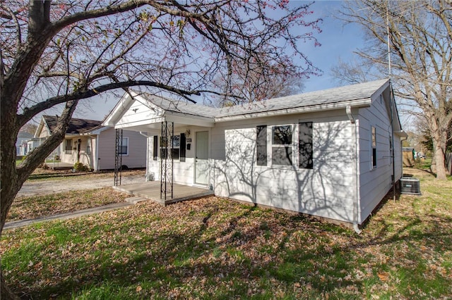 view of front of home featuring a front yard, cooling unit, and covered porch