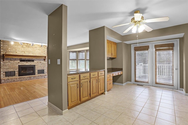 kitchen with ceiling fan, rail lighting, a fireplace, built in desk, and light wood-type flooring