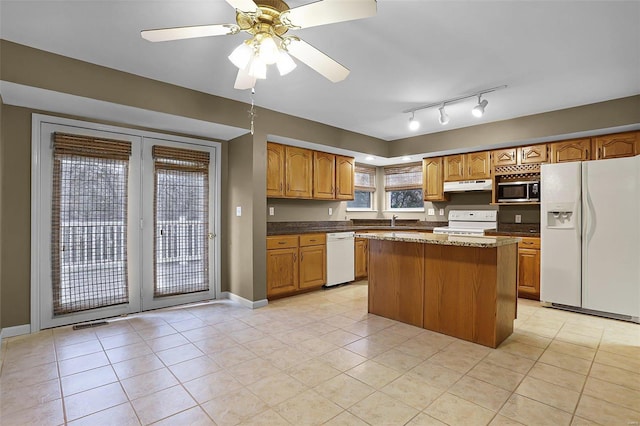 kitchen with white appliances, ceiling fan, sink, light tile patterned floors, and a kitchen island