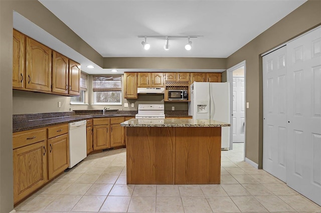 kitchen featuring a center island, white appliances, sink, dark stone countertops, and light tile patterned floors