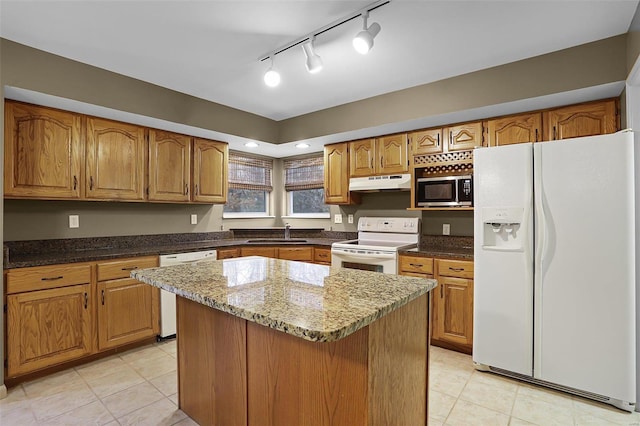 kitchen featuring track lighting, white appliances, sink, a kitchen island, and light tile patterned flooring