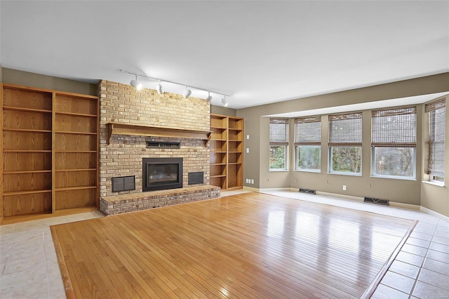 unfurnished living room with rail lighting, a fireplace, and light hardwood / wood-style flooring