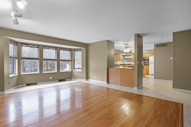 unfurnished living room featuring ceiling fan and light hardwood / wood-style floors