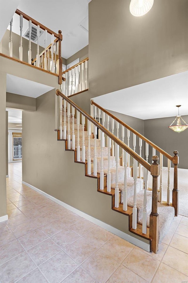 stairway with tile patterned floors and a high ceiling