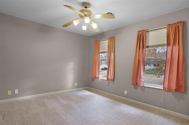 carpeted spare room featuring ceiling fan and a wealth of natural light