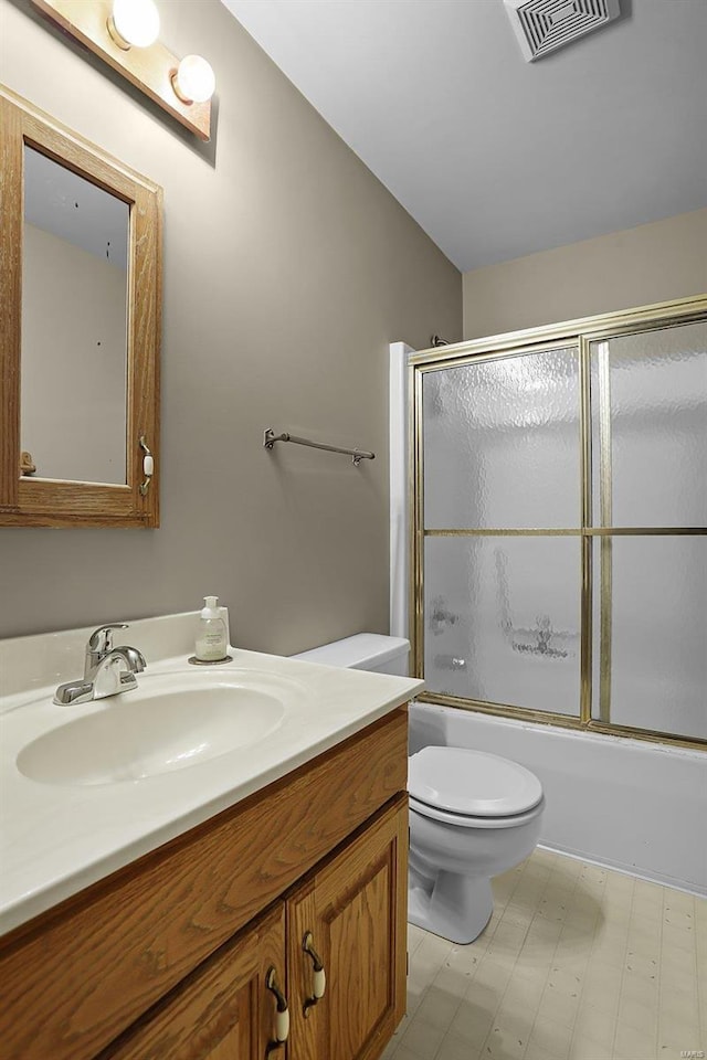 full bathroom featuring vanity, bath / shower combo with glass door, and toilet