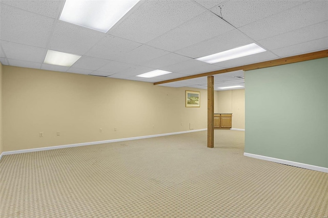 basement with a paneled ceiling and light colored carpet