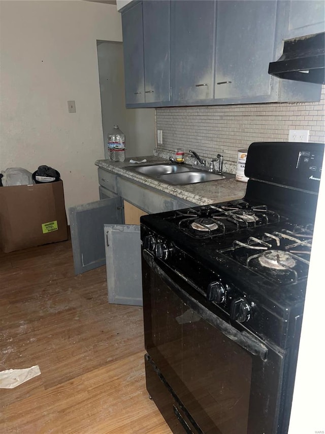 kitchen featuring sink, light hardwood / wood-style flooring, range hood, black range with gas cooktop, and decorative backsplash