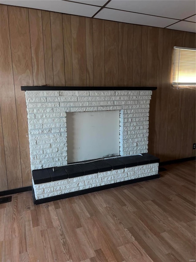 room details featuring a paneled ceiling, wooden walls, and wood-type flooring