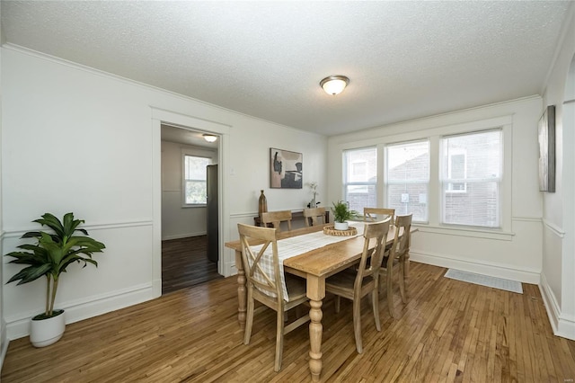 dining area featuring crown molding, dark wood-type flooring, and a textured ceiling