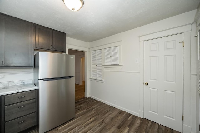 kitchen with dark brown cabinets, dark hardwood / wood-style flooring, a textured ceiling, and stainless steel refrigerator