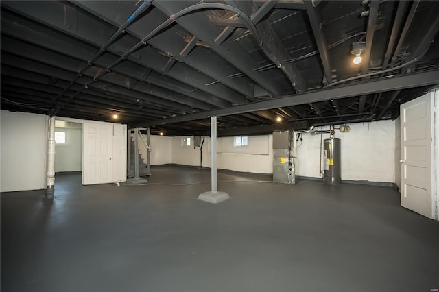 basement with heating unit, water heater, and a wealth of natural light