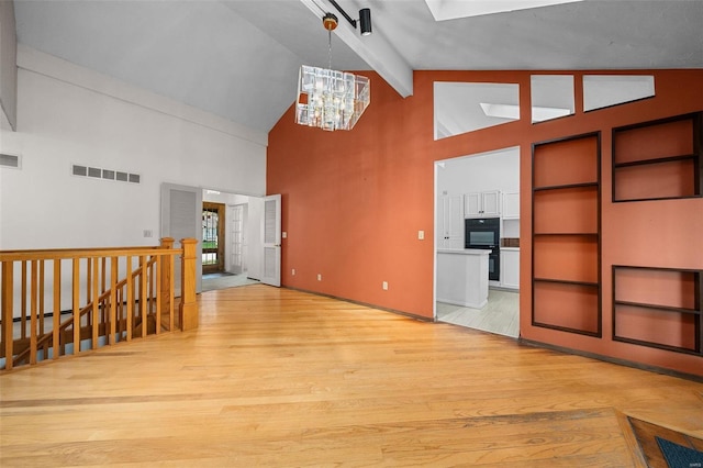 living room featuring beamed ceiling, light hardwood / wood-style floors, high vaulted ceiling, and a notable chandelier