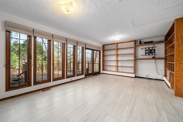 unfurnished room with light wood-type flooring and a textured ceiling