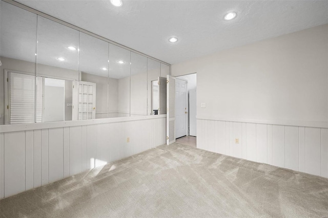 carpeted empty room featuring wooden walls and a textured ceiling