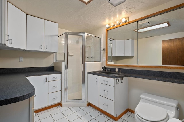 bathroom featuring vanity, a shower with door, tile patterned floors, toilet, and a textured ceiling