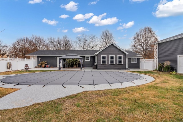 rear view of house featuring a gazebo, a patio area, a yard, and a covered pool