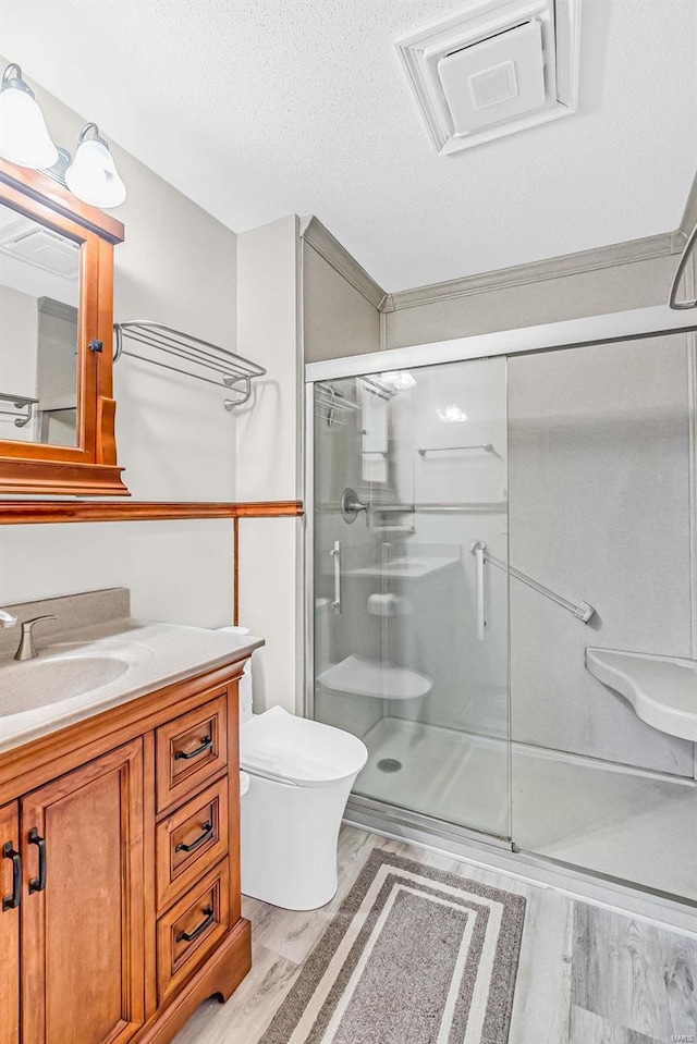 bathroom featuring hardwood / wood-style floors, toilet, a shower with door, and a textured ceiling