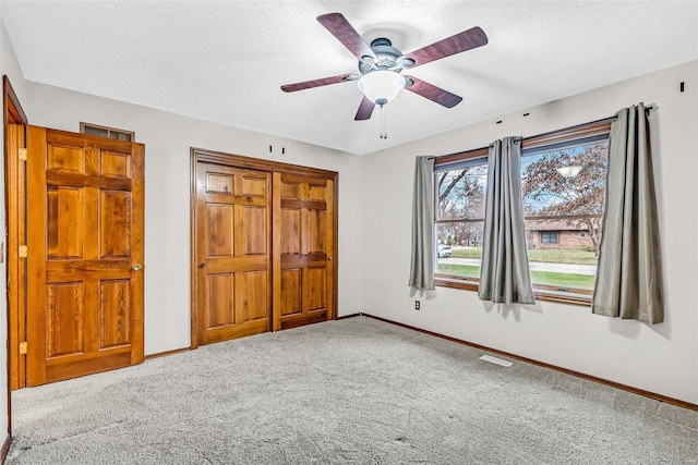 unfurnished bedroom with carpet, a textured ceiling, and ceiling fan