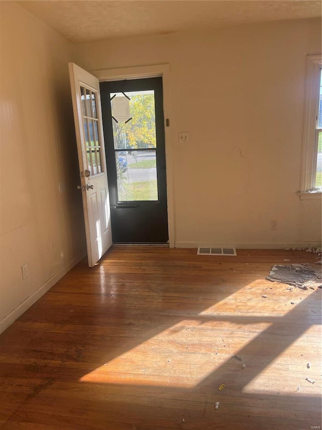 spare room with a textured ceiling, hardwood / wood-style flooring, and plenty of natural light