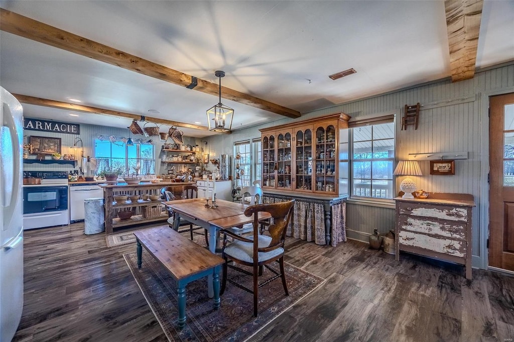 dining room featuring beam ceiling, dark wood-type flooring, and an inviting chandelier