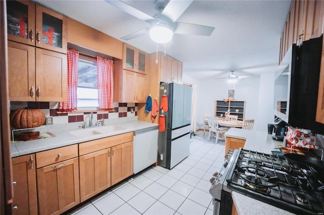 kitchen with backsplash, white dishwasher, refrigerator, stainless steel range with gas cooktop, and sink